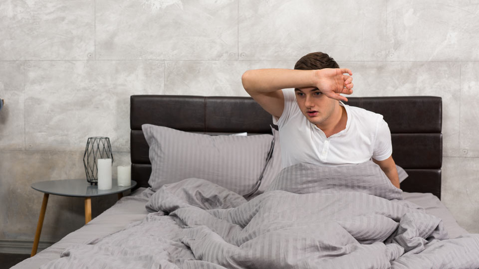 https://www.therapmed.ch/wp-content/uploads/2021/11/terrified-young-man-woke-up-from-a-nightmare-and-wiping-sweat-from-his-forehead-while-sitting-in-stylish-bed-with-grey-colors-in-a-bedroom-in-loft-style.jpg